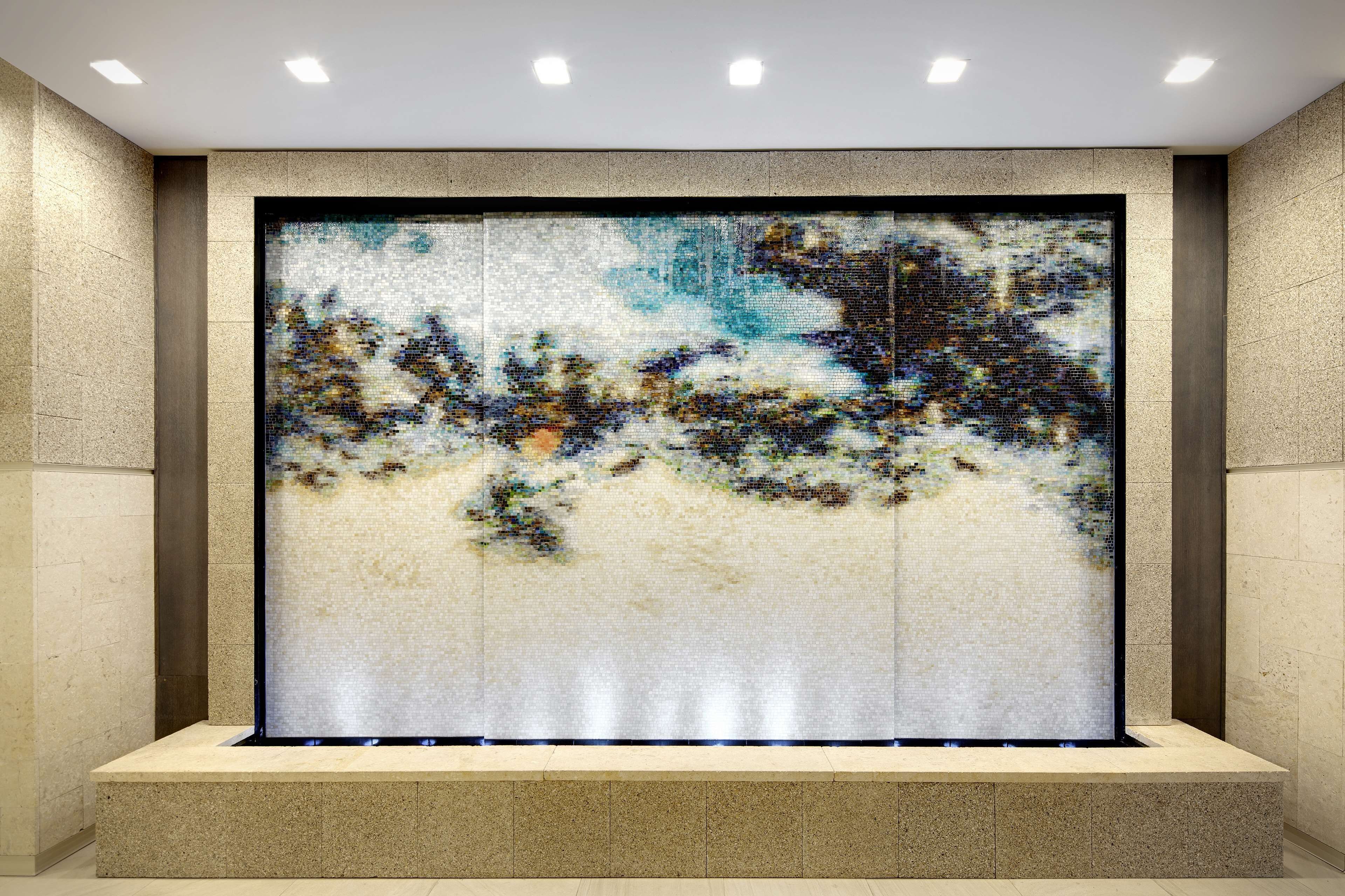 A large, abstract mosaic wall with a recessed seating area in front.