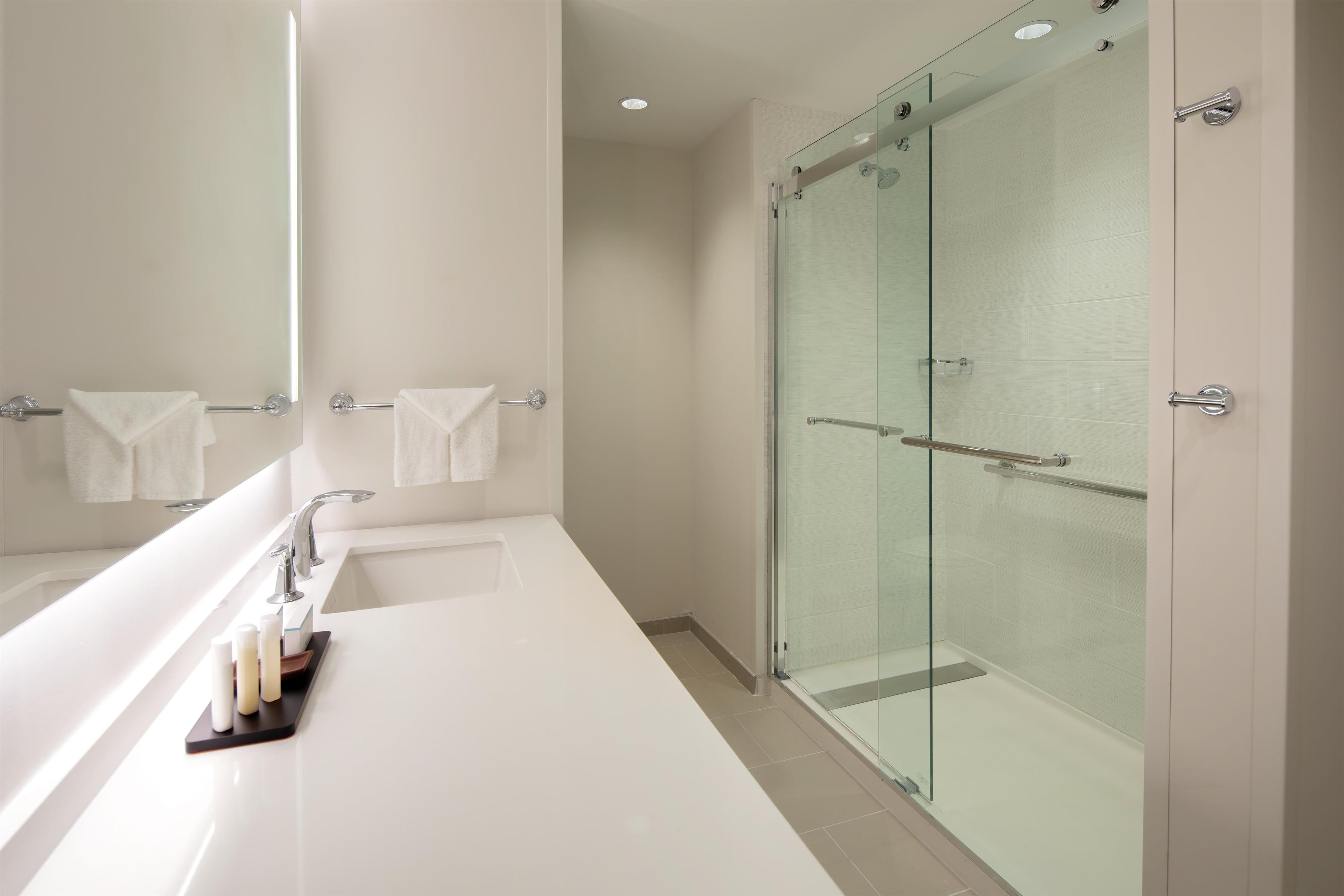 Ein modernes Badezimmer mit einer Duschkabine, einer großen weißen Badewanne und einem Waschtisch mit Spiegel und Handtuchhalter.