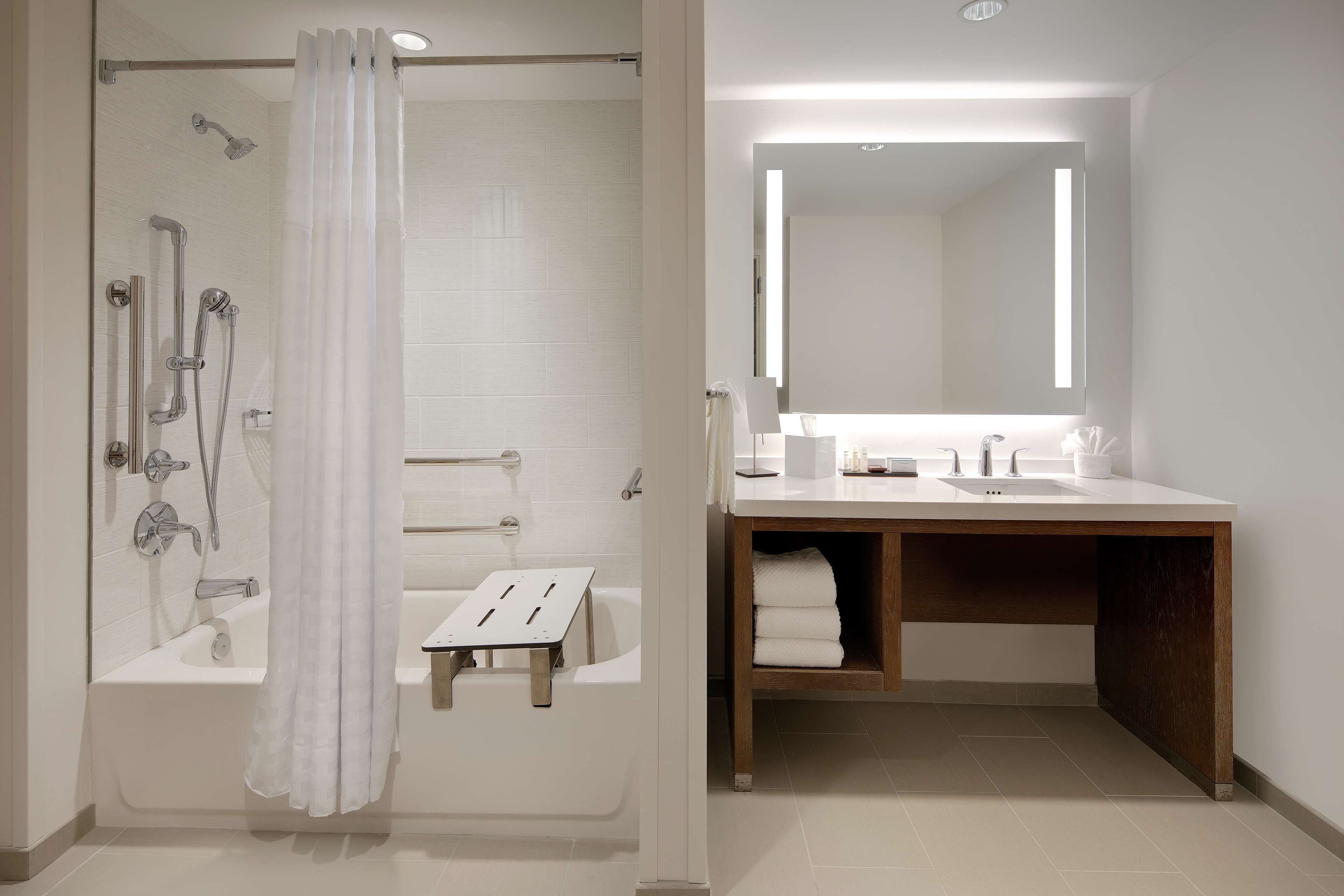 Ein modernes Badezimmer mit Dusche, Badewanne, Waschtisch inklusive Spiegel und Handtuchhalter.