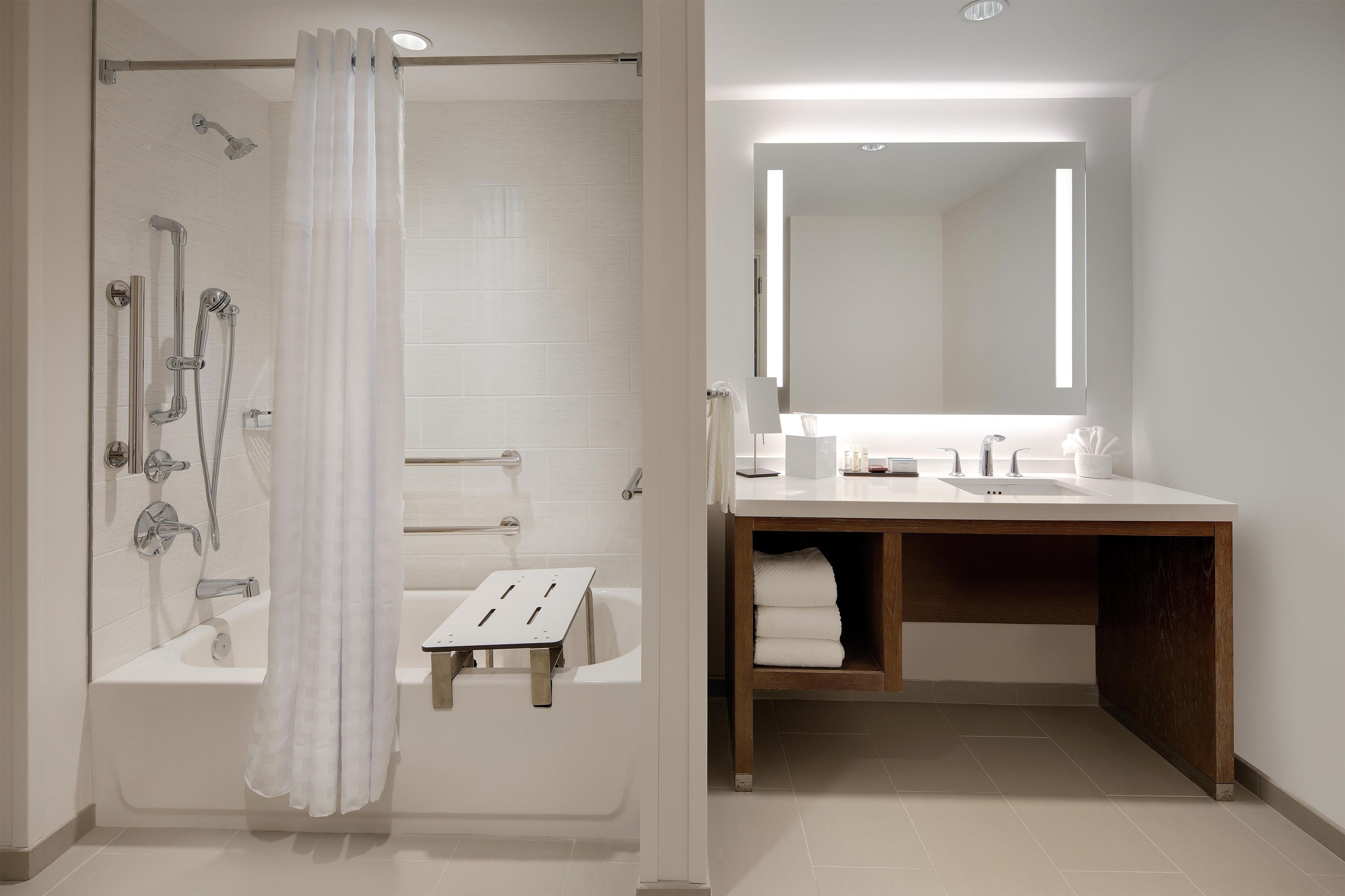Ein modernes Badezimmer mit Dusche, Badewanne, Waschtisch und Spiegel sowie einem Handtuchhalter.