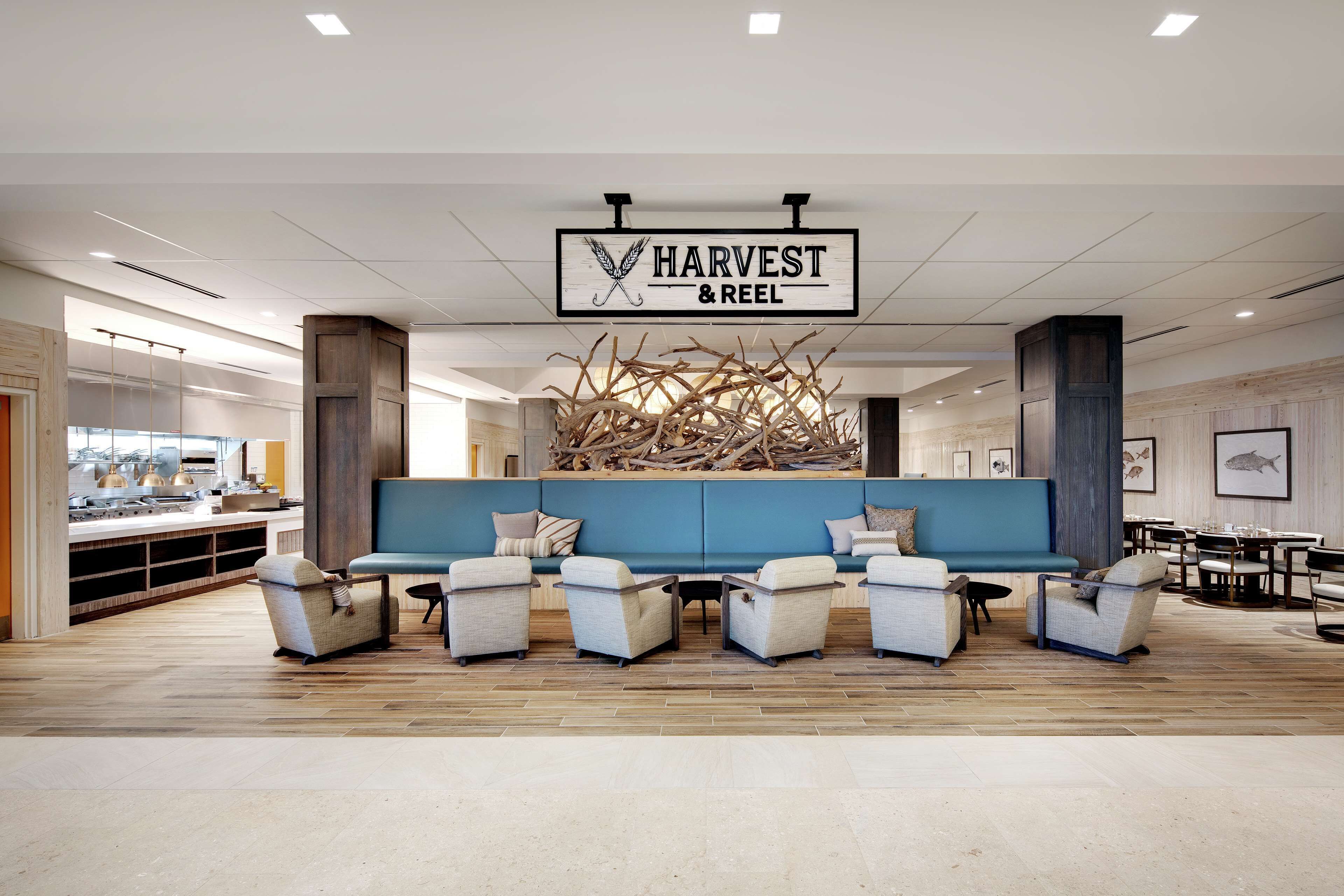 A modern lobby with a blue sofa, white armchairs, and a wooden sculpture.