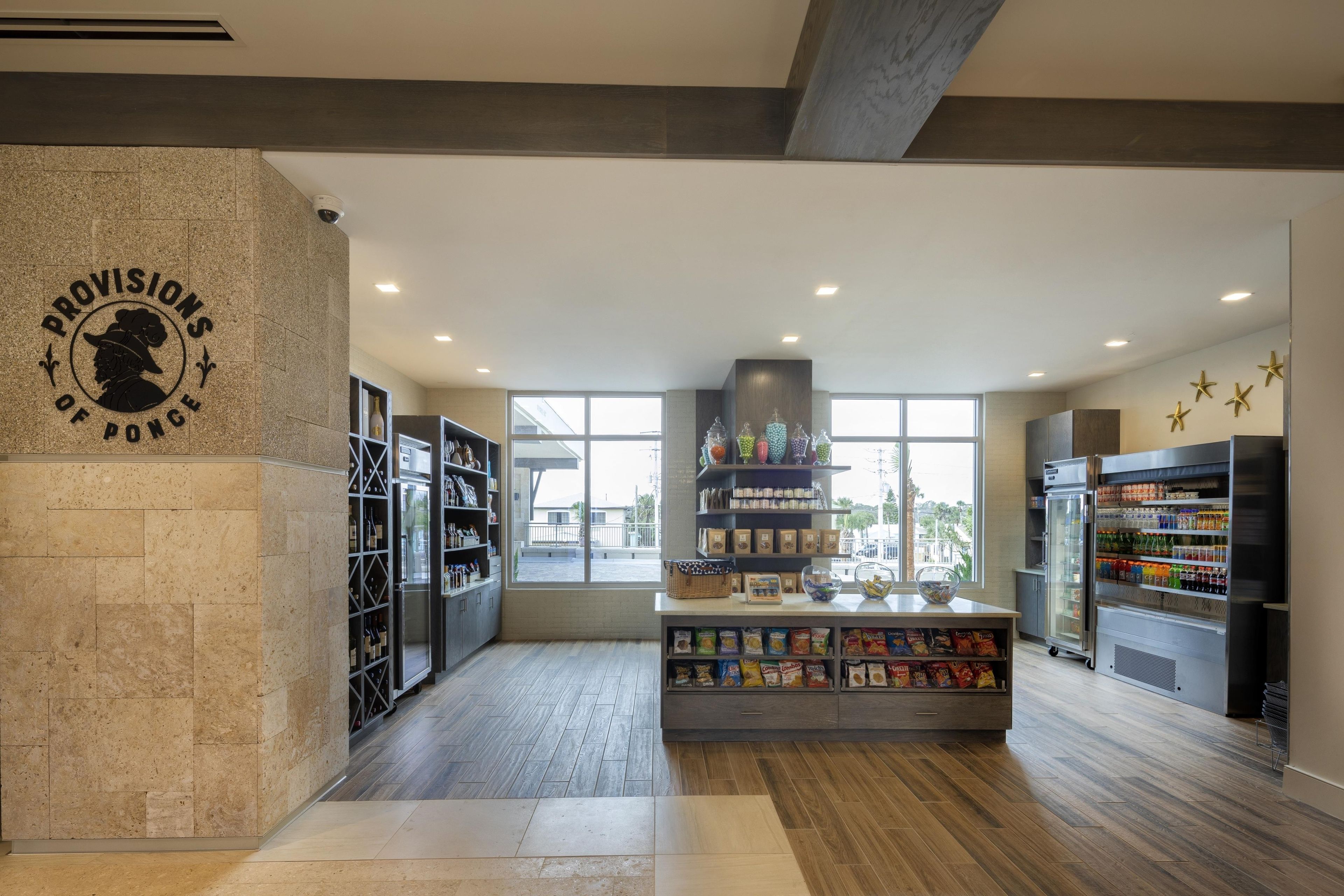 A modern kitchen with a stone accent wall, wine and snack dispensers, and a view through large windows.