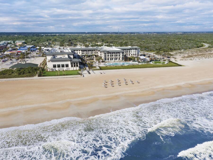 A beachfront hotel with multiple buildings, a swimming pool, and a beach area.