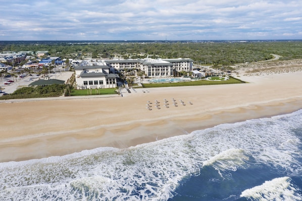 Un hôtel situé en bord de mer, composé de plusieurs bâtiments, doté d’une piscine et d’un espace de plage.