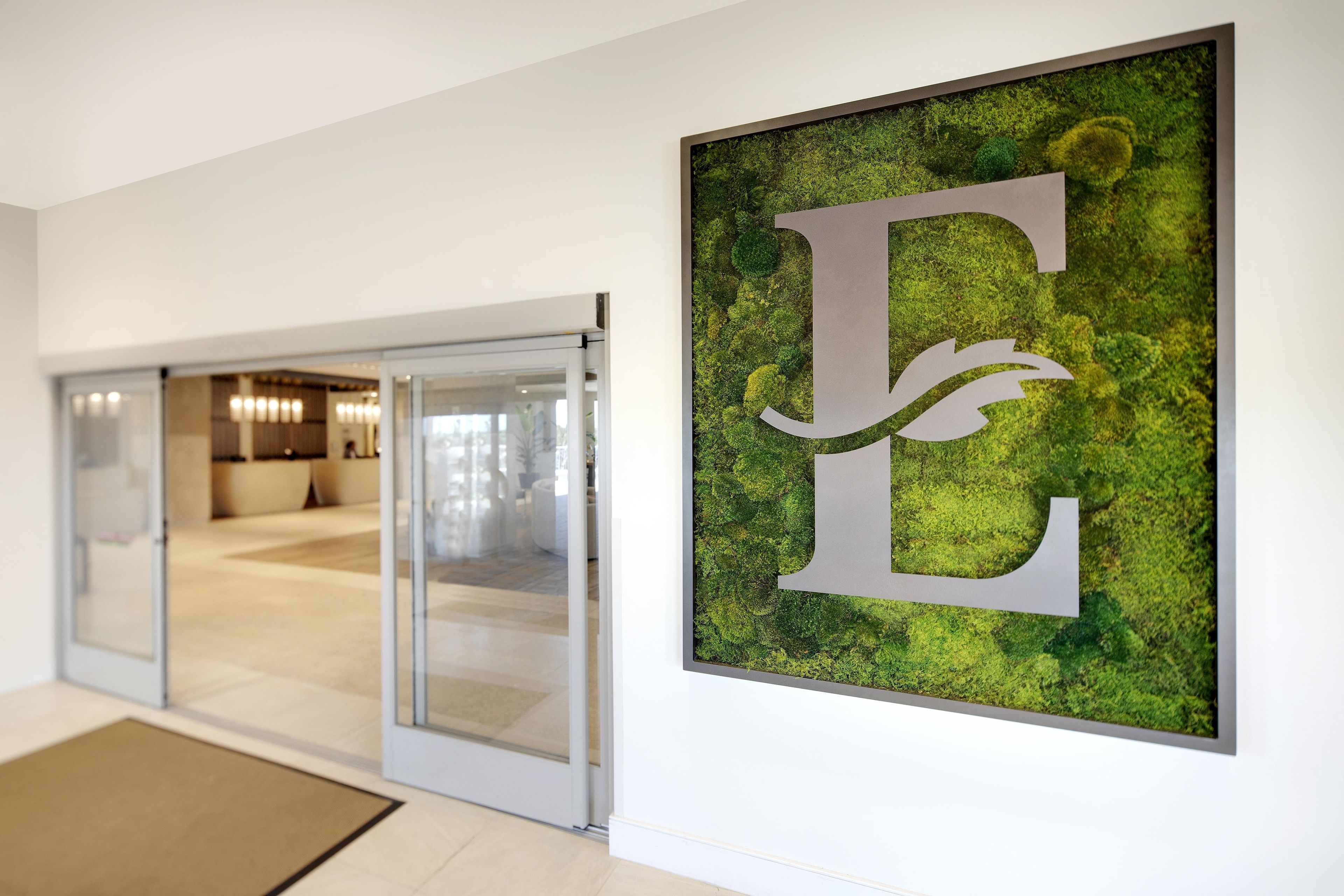 A hallway with a glass door leading to a seating area, and a large letter 'E' on the wall.