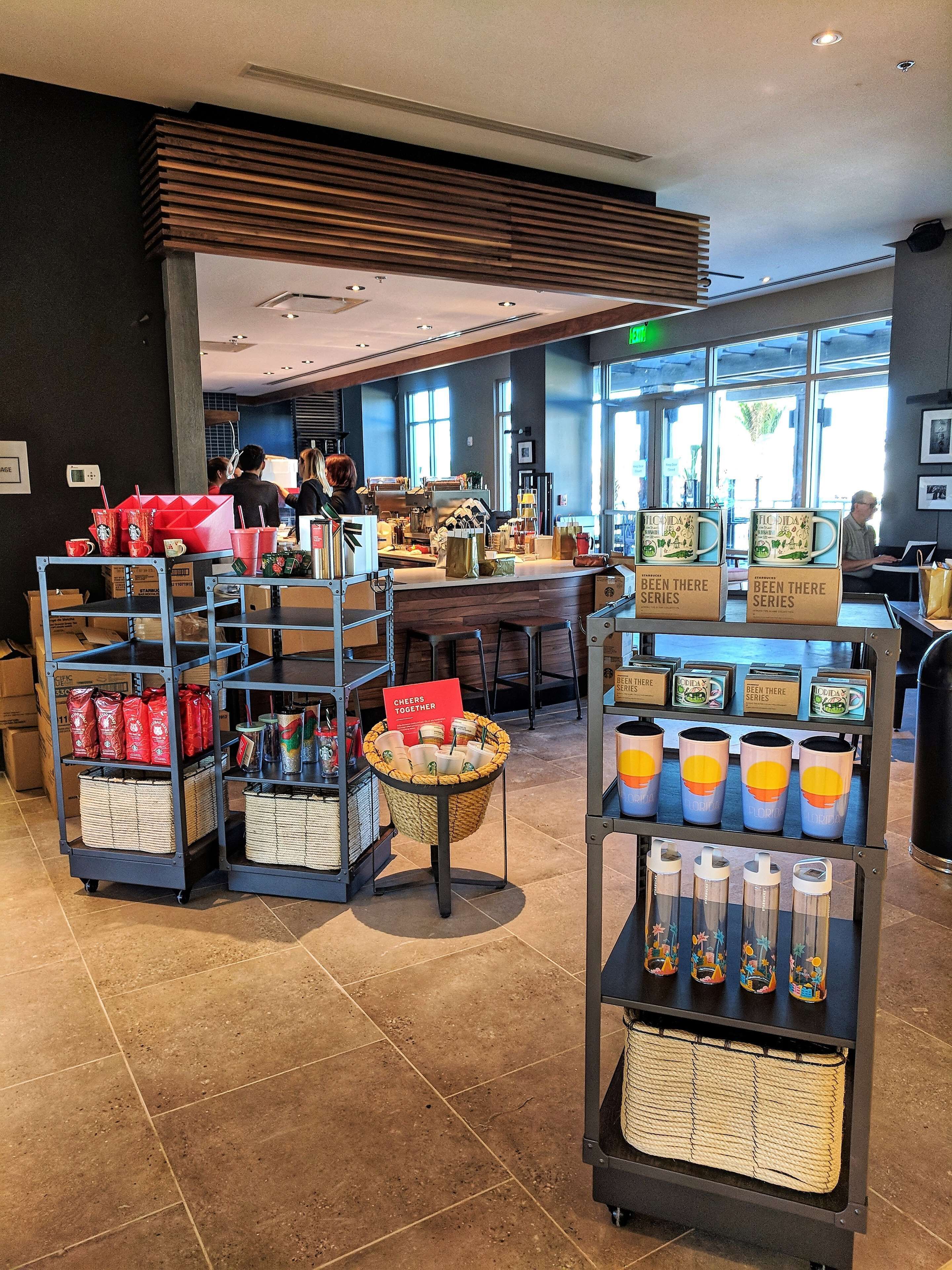 A coffee shop interior with a counter, shelves with bags and cups, and a display of mugs.