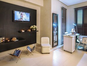 A modern hotel lobby with a TV, seating area, reception desk, and a magazine rack. - Mövenpick Hotel Gammarth Tunis (La Marsa)