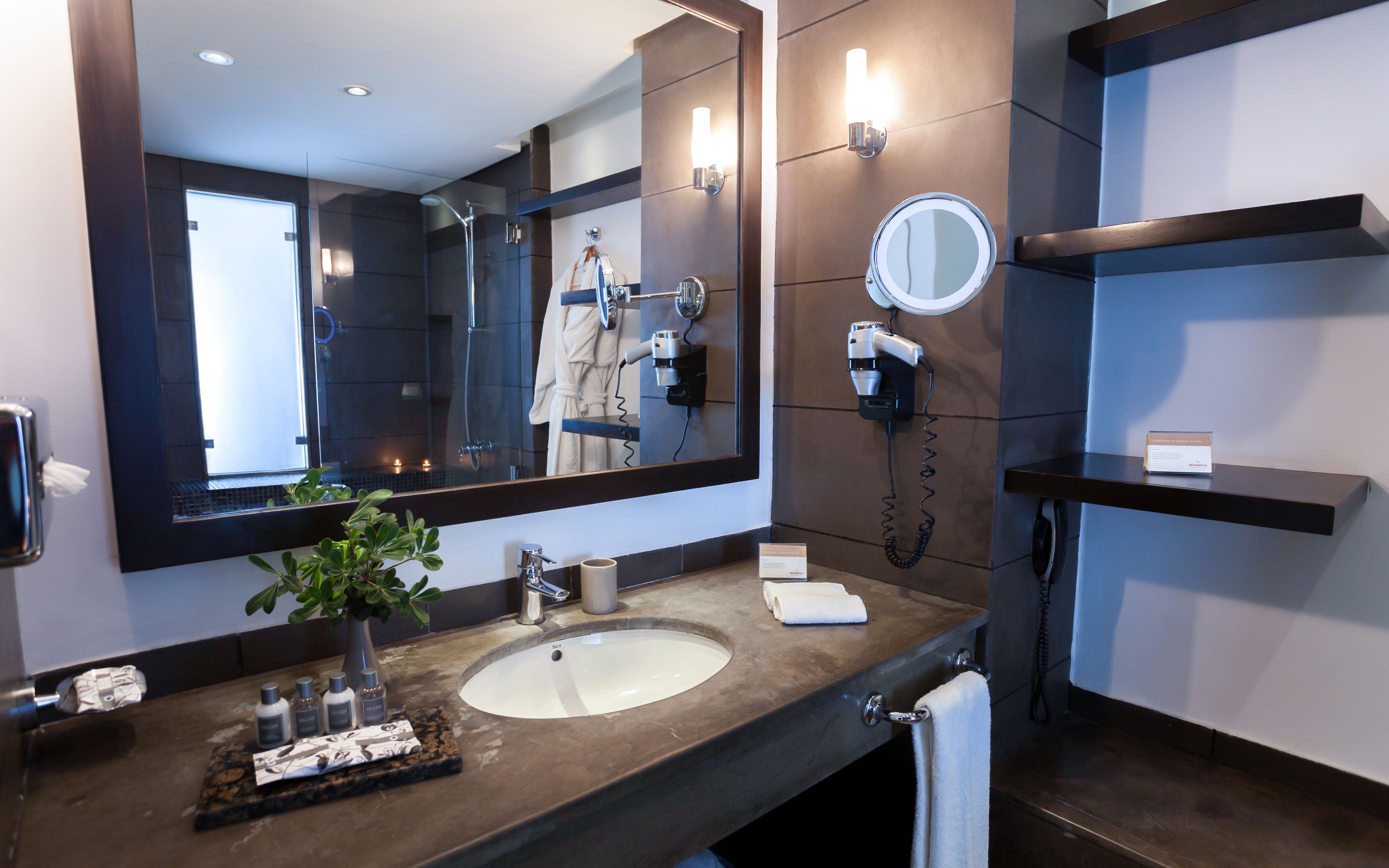 Un baño moderno con un espejo grande, un lavamanos, un secador de pelo y un tendedero para toallas.