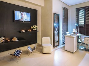 A modern hotel lobby with a TV, seating area, reception desk, and a magazine rack. - Mövenpick Hotel Gammarth Tunis (La Marsa)