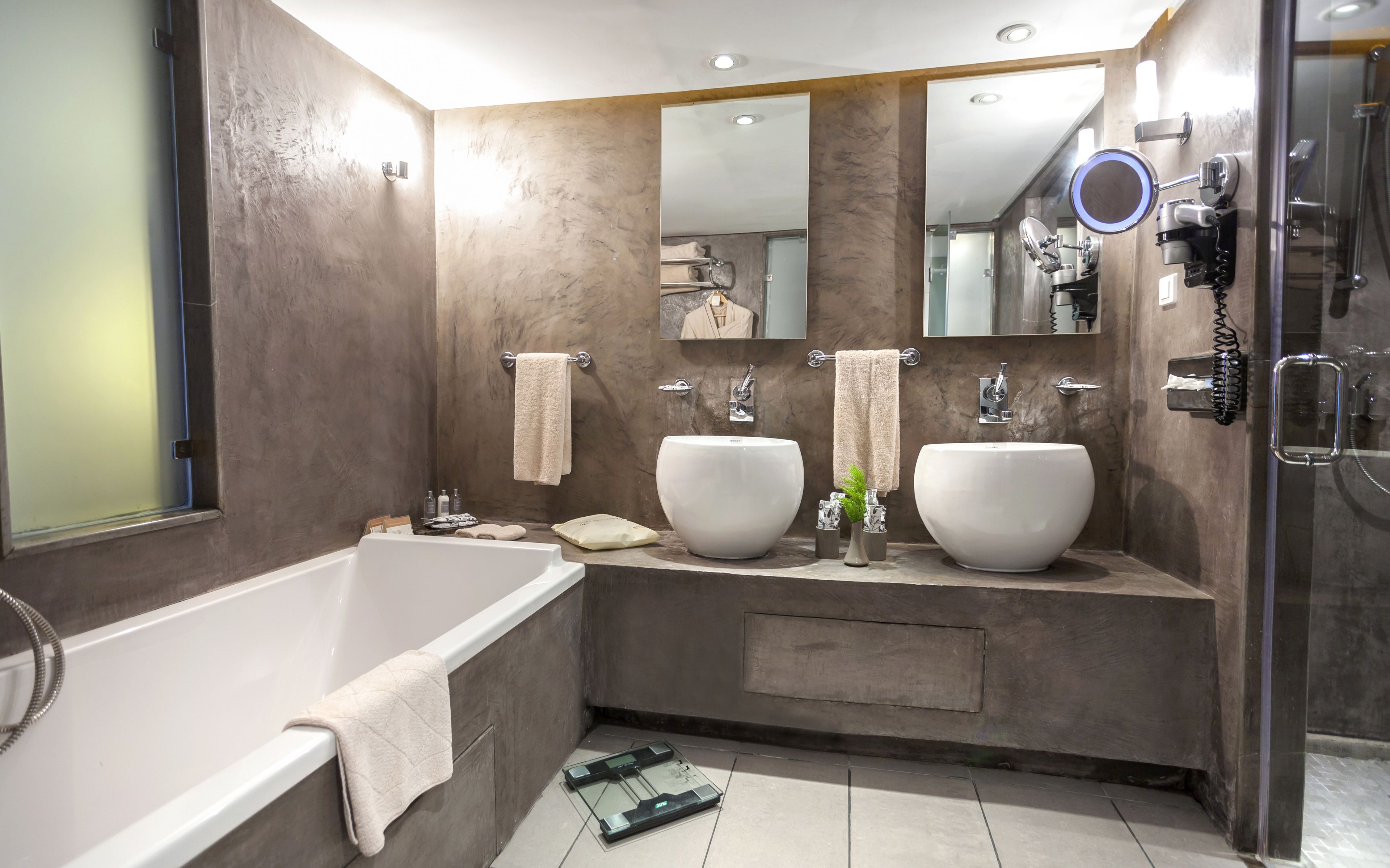Une salle de bain moderne avec deux grands lavabos, une baignoire et une douche à l’italienne.
