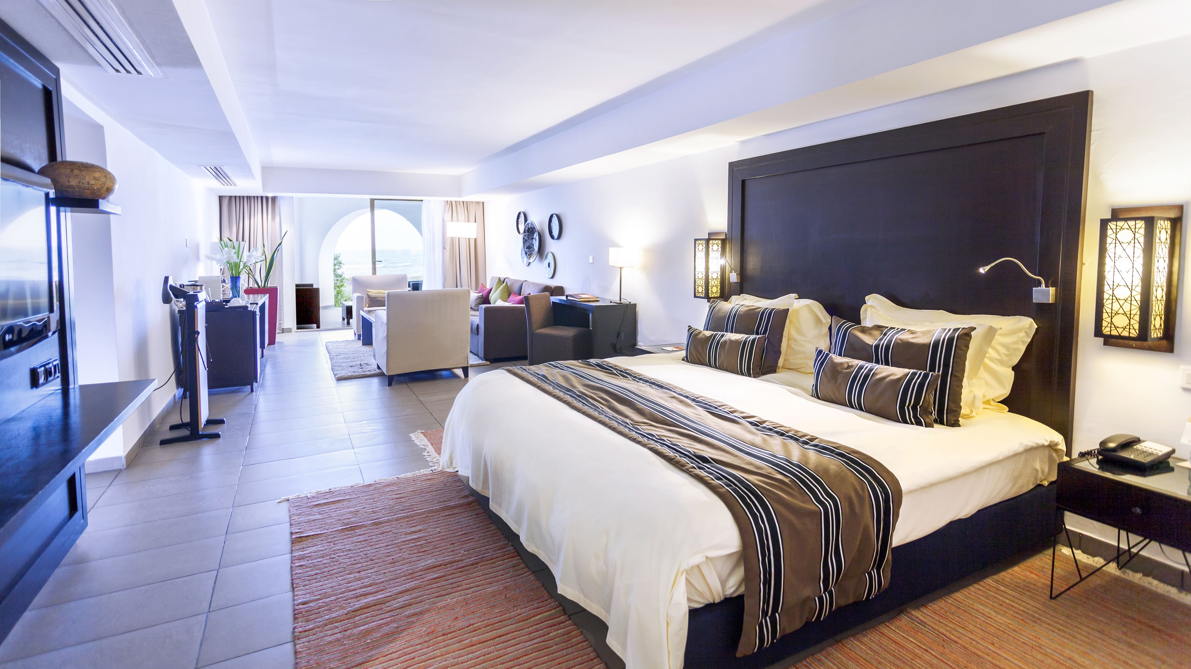 Una habitación de hotel moderna con una cama grande, un escritorio y una zona de estar.