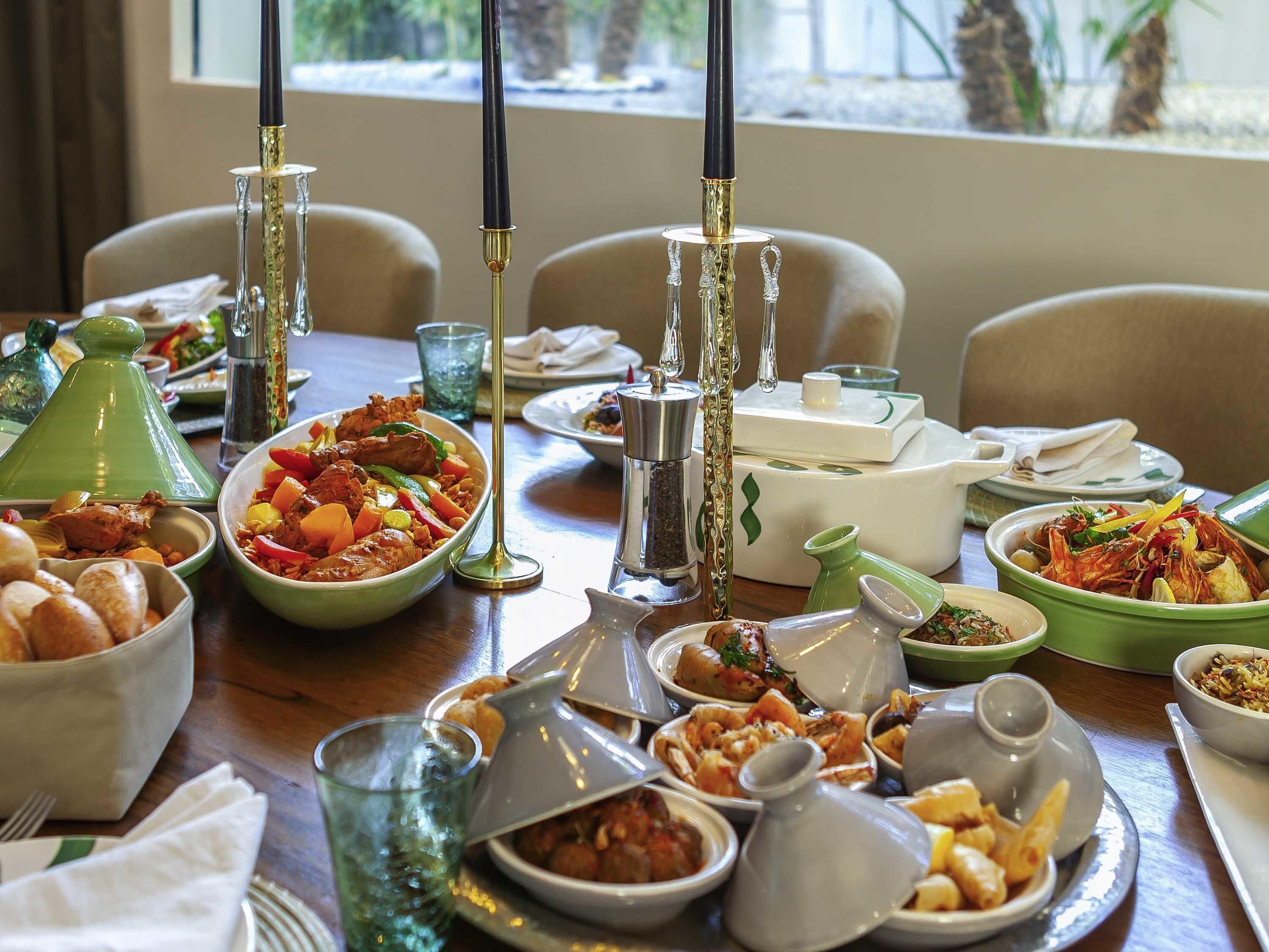 Une table à manger avec différents plats, des verres et un service à thé marocain traditionnel.