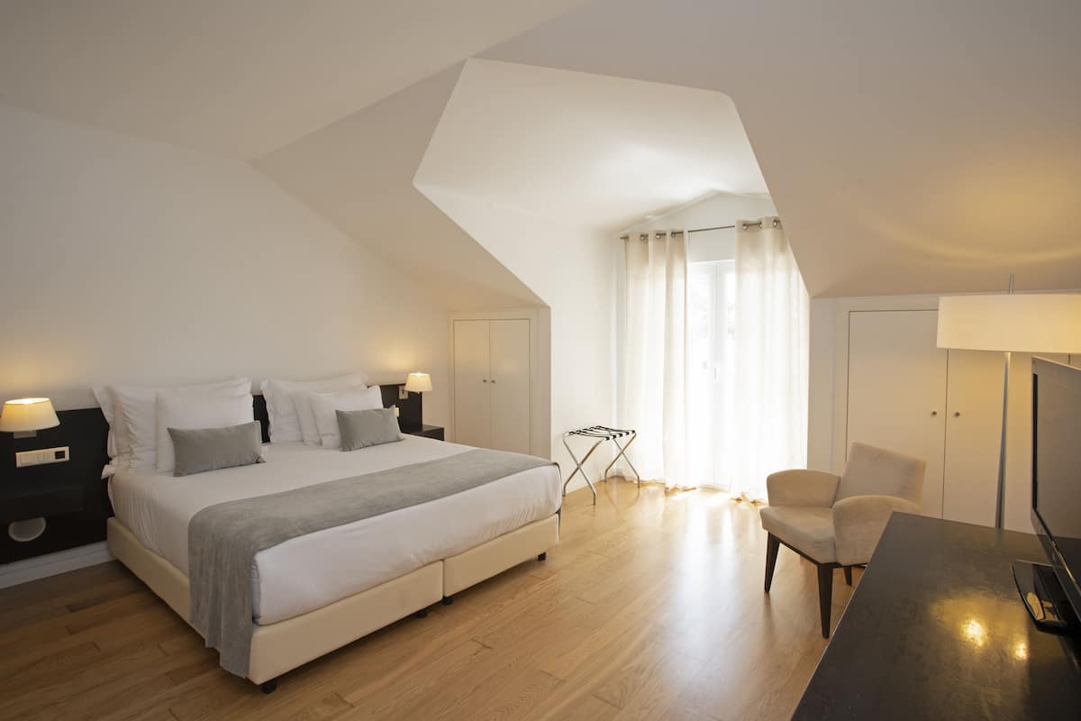 Une chambre moderne avec un grand lit, des tables de chevet, une chaise et un bureau.