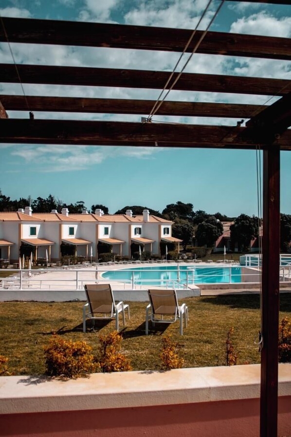 Un espace piscine avec des chaises longues et une vue sur une rangée de bâtiments.
