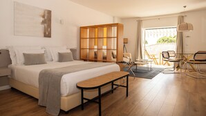 Um quarto moderno com uma cama grande, um painel de madeira, um banco e vista para o exterior.