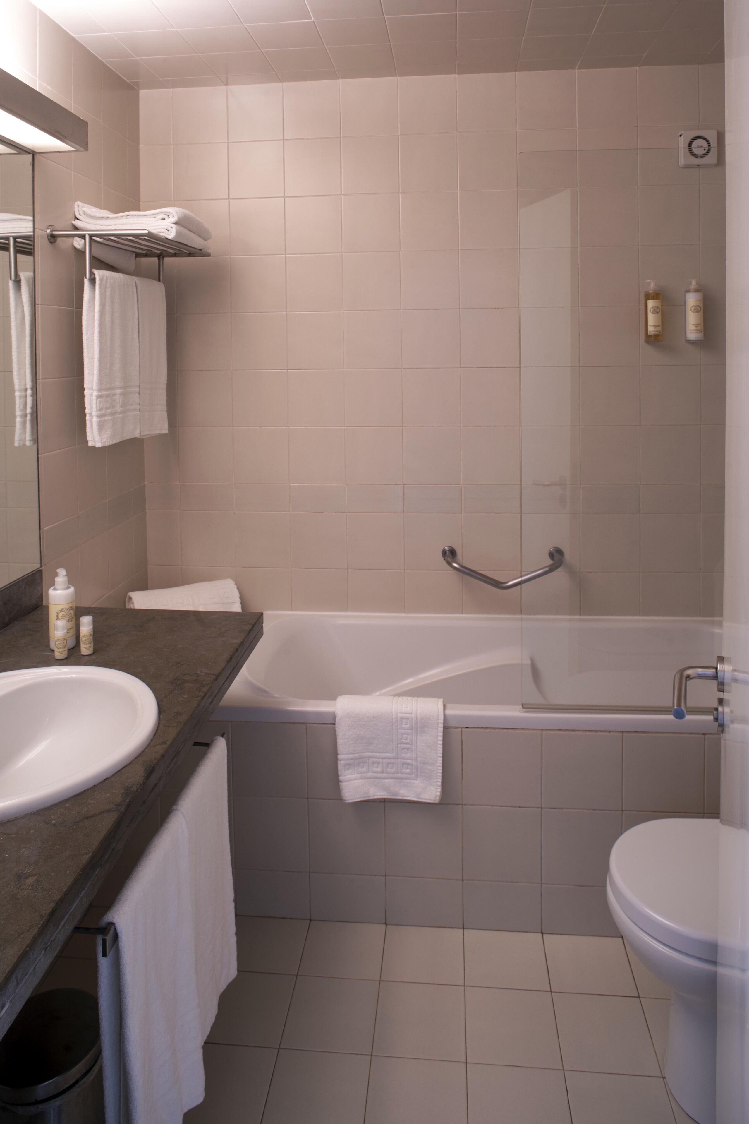 Une salle de bain moderne avec une baignoire, des toilettes et un lavabo. On y trouve des serviettes et des articles de toilette sur le comptoir.