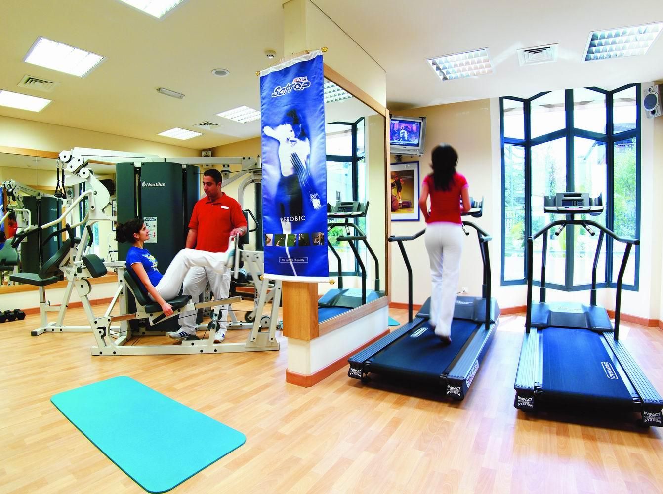 A gym with treadmills, weight machines, and a blue mat on the floor.