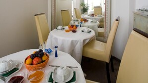 A dining area with two tables, each set with white tablecloths, plates, and bowls of fruit. A large mirror reflects the room, and there is a framed picture on the wall. - Goldener Hecht (Heidelberg)