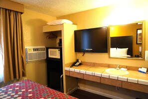 A hotel room with a bed, a bathroom with a sink, a mirror, and a television.
