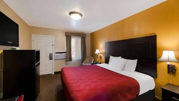 A hotel room with a bed, a desk, a television, and a door.