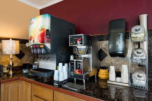 A coffee station with a branded beverage dispenser, a coffee maker, and various coffee accessories.