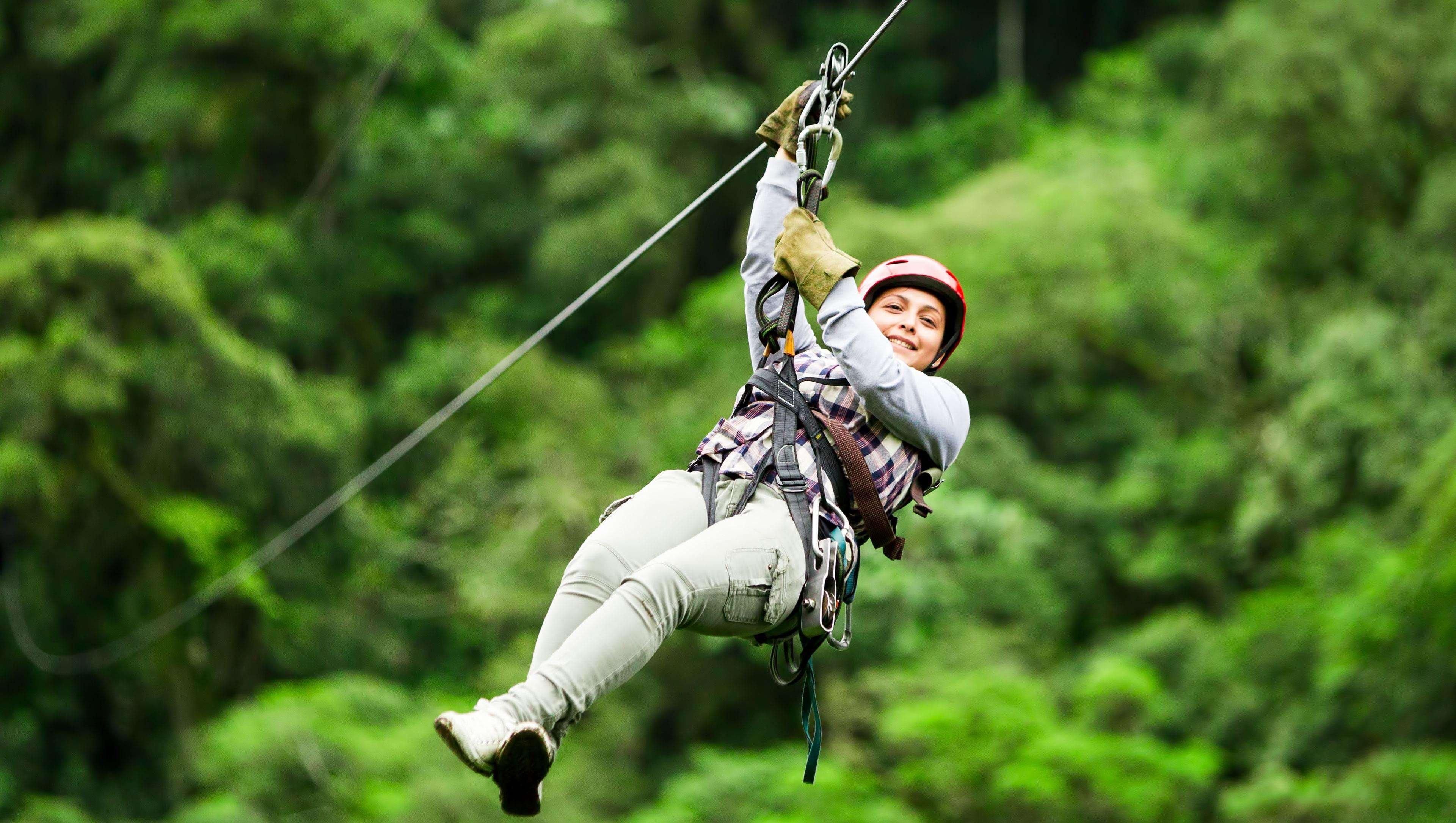 A person zip-lining through a forested area.