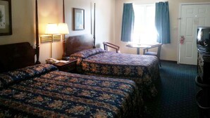 A hotel room with two beds, a desk, a chair, a television, and a window with curtains.
