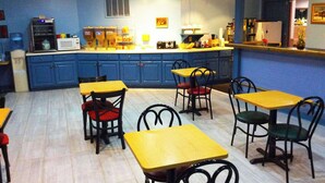 A dining area with blue cabinets, yellow tables, and black chairs. - Stratford Motor Inn East Ellijay (Ellijay)