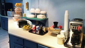 A kitchenette with a coffee maker, sugar, creamer, and a fruit basket. - Stratford Motor Inn East Ellijay (Ellijay)