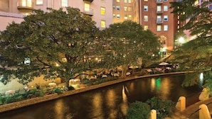 A riverside hotel with outdoor seating, a brick facade, and multiple balconies. - Club Wyndham Riverside Suites (San Antonio)