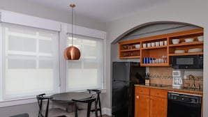 A modern kitchen with a black refrigerator, wooden cabinets, and a dining area with a table and chairs. - Club Wyndham Riverside Suites (San Antonio)