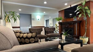 Ein Wohnzimmer mit einer Couch, Sesseln, einem Couchtisch, einem Kamin und einem Fernseher.