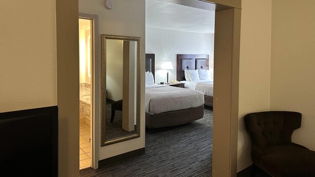 Ein Hotelzimmer mit Bett, Nachttisch, Lampe und Spiegel.
