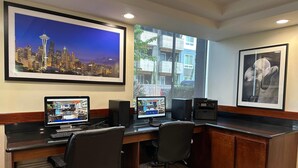 Ein modernes Büro mit zwei Schreibtischen, Computern und einem großen Bild einer Stadtansicht im Rahmen.