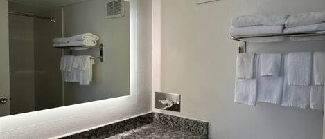 Une salle de bain avec un comptoir en granit, un lavabo, un miroir, un porte-serviettes et des toilettes.