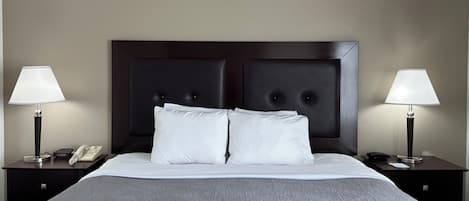A hotel room with a large bed, two bedside tables, a telephone, and two lamps.