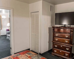 A hotel room with a bed, a dresser, a television, and a closet. - Suburban Studios Tallahassee near University (Tallahassee)