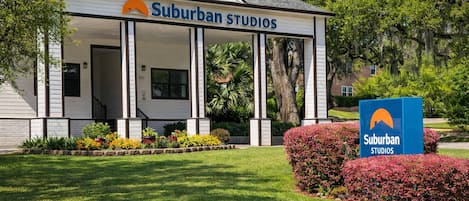 A building with a sign reading 'Suburban Studios' and a smaller sign with the same logo.