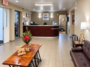 Een hotel receptie met een receptiebalie, een kerstboom, een salontafel met een decoratie van een eland, en een bank.