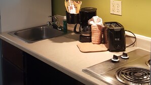 A kitchen with a microwave, coffee maker, toaster, and a sink. - Suburban Studios Tallahassee near University (Tallahassee)