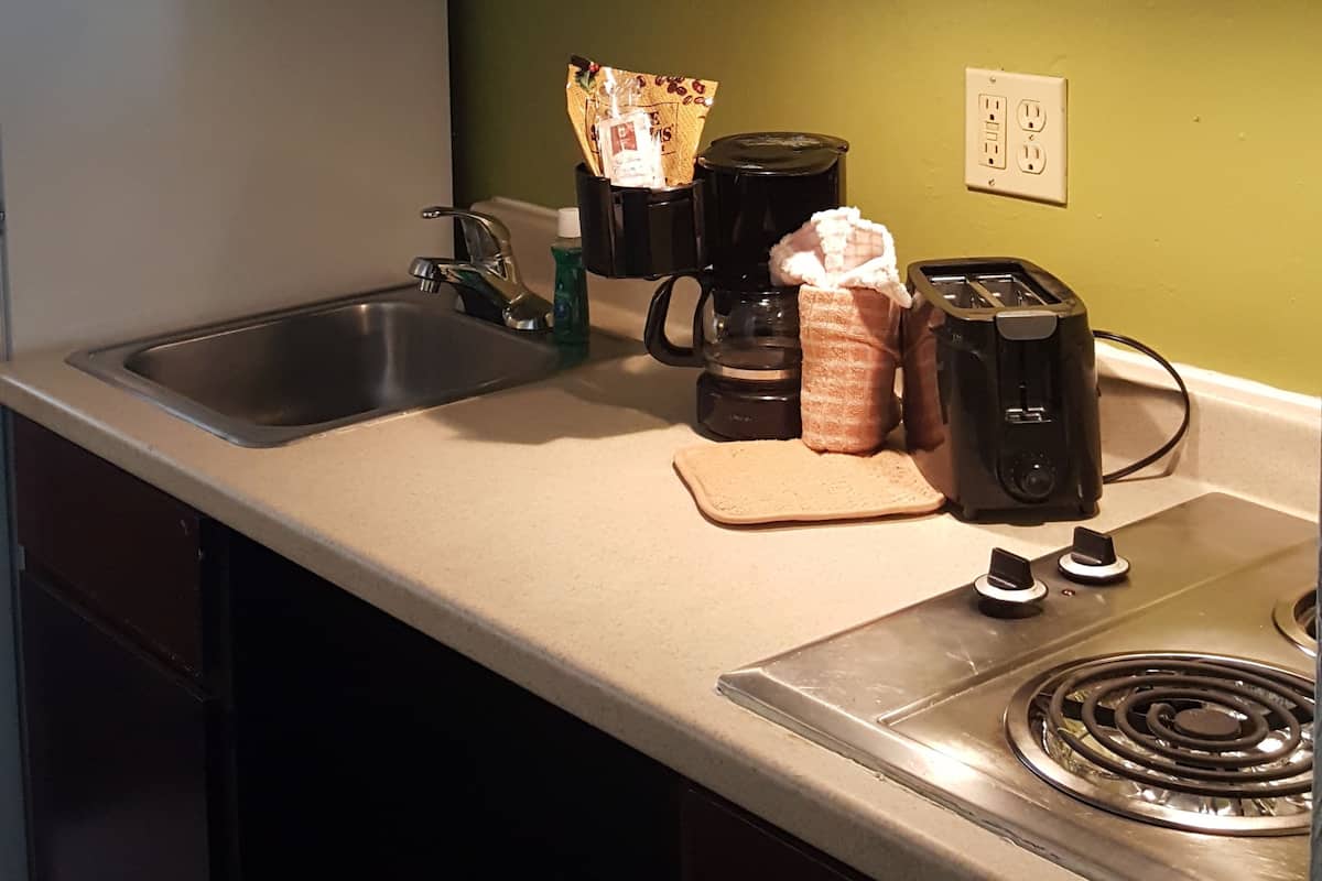 A kitchen with a microwave, coffee maker, toaster, and a sink.