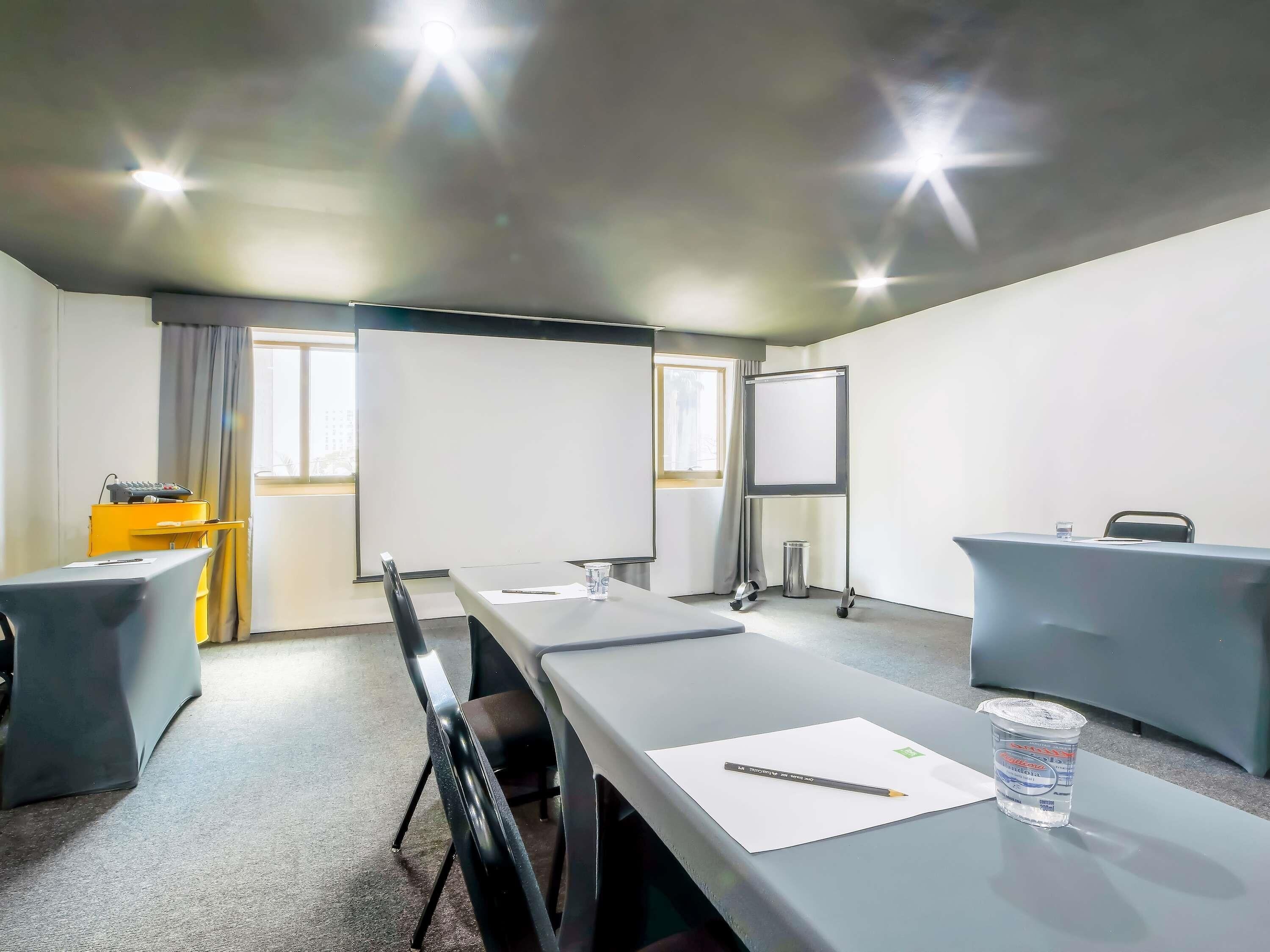A conference room with a long table, chairs, a projector screen, and a whiteboard.