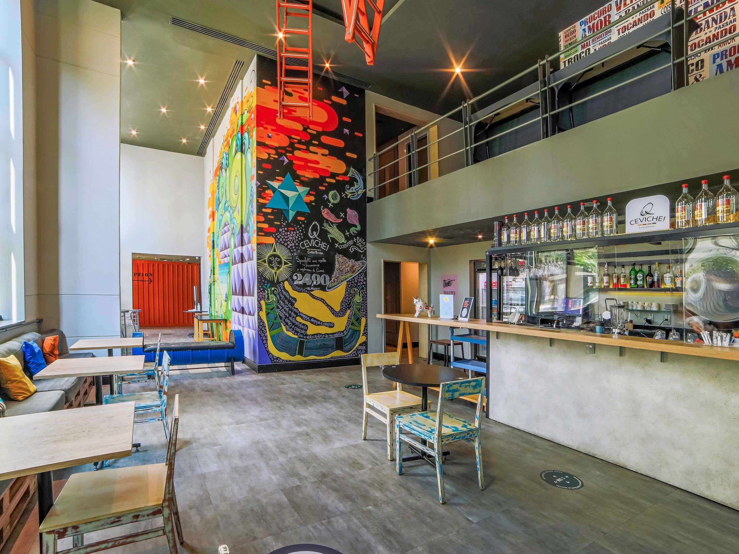 A bar area with a colorful mural, seating, and a bar counter with bottles.