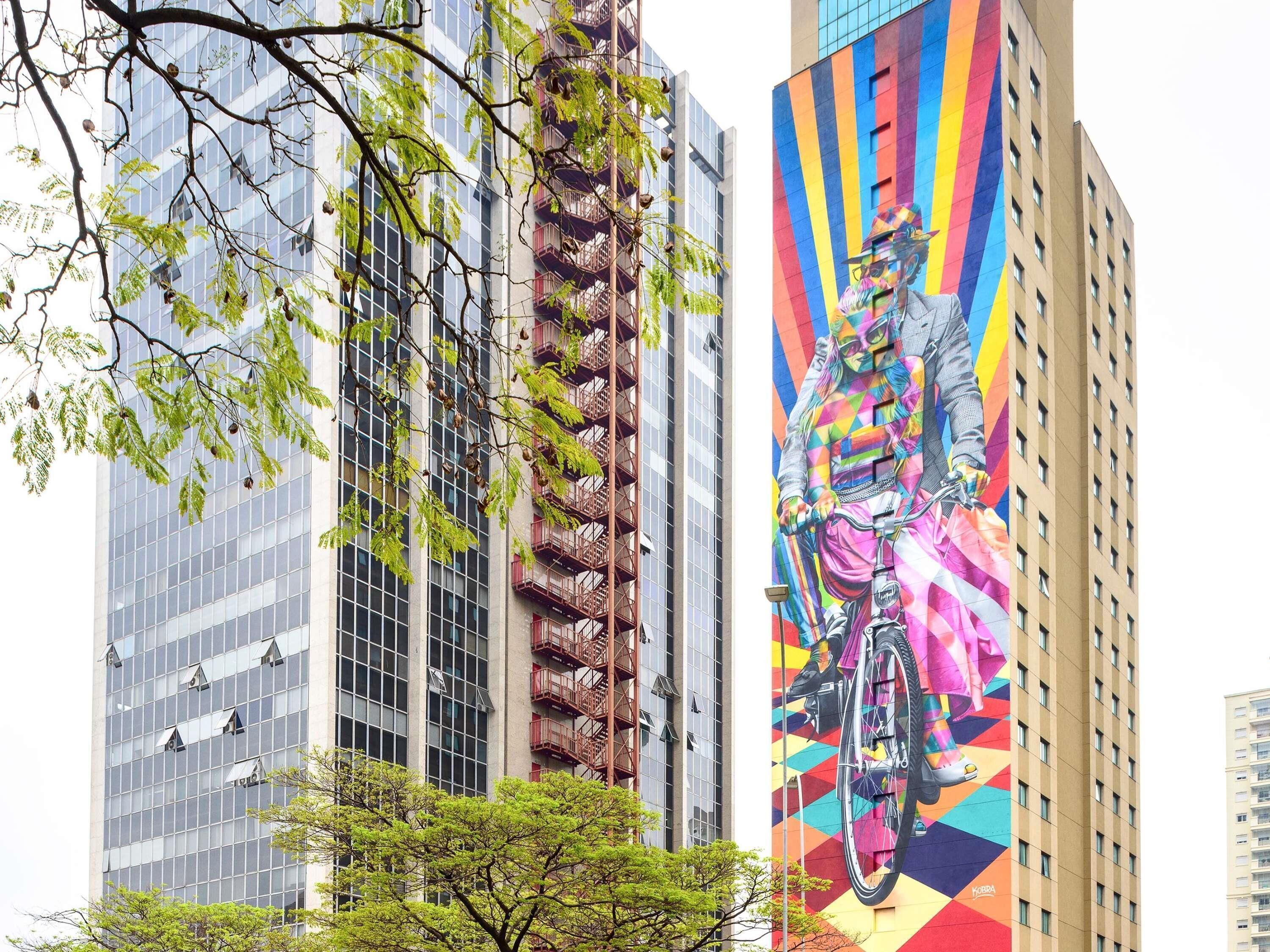 A high-rise building with a large mural of a cyclist on the side.