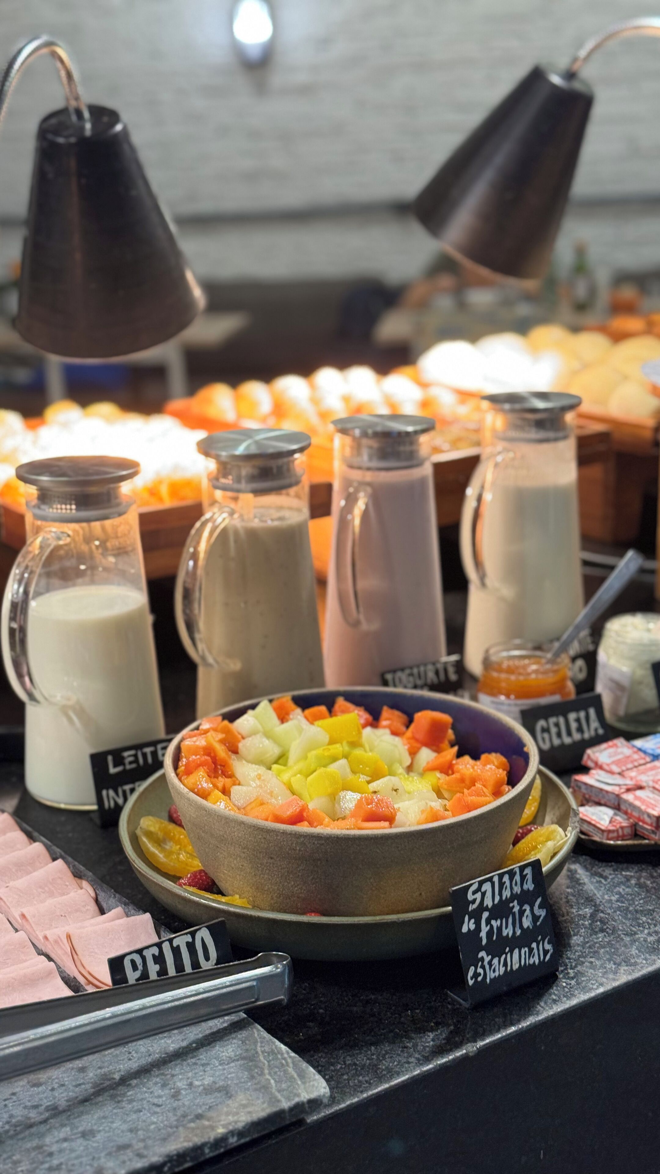 Exposição de alimentos com diversos produtos lácteos e uma tigela de salada de frutas.