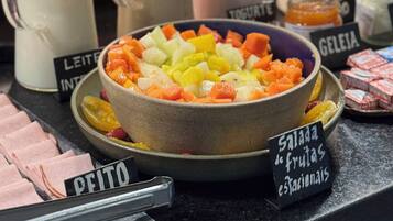 Exposição de alimentos com diversos produtos lácteos e uma tigela de salada de frutas.