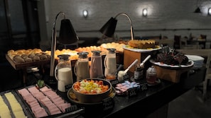 A buffet with various food items including meats, fruits, and condiments. - ibis Styles SP Faria Lima (São Paulo)