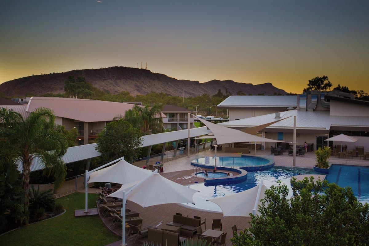 A resort with a pool area, outdoor seating, and a view of a mountain.