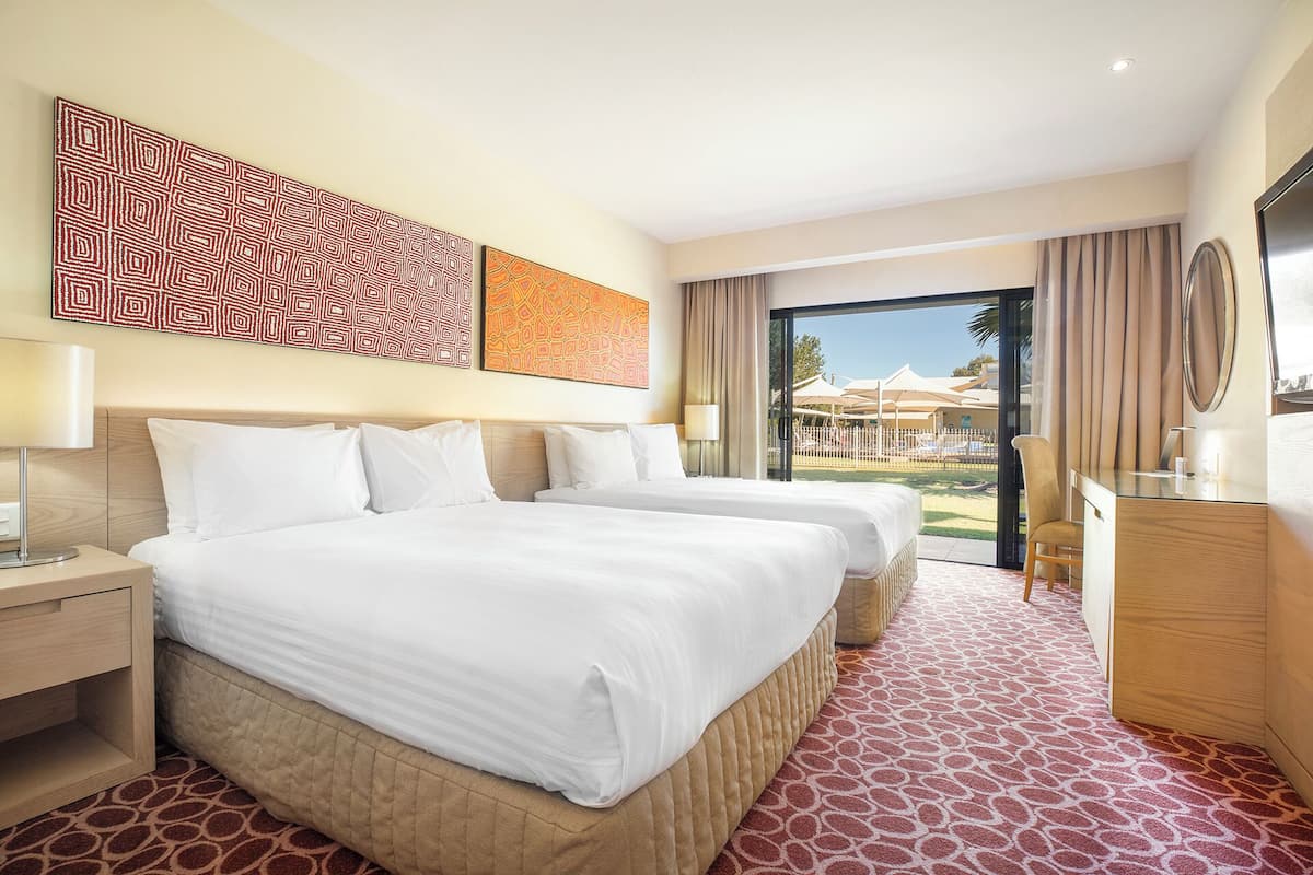 A hotel room with a large bed, a desk, and a view of the outdoor area.