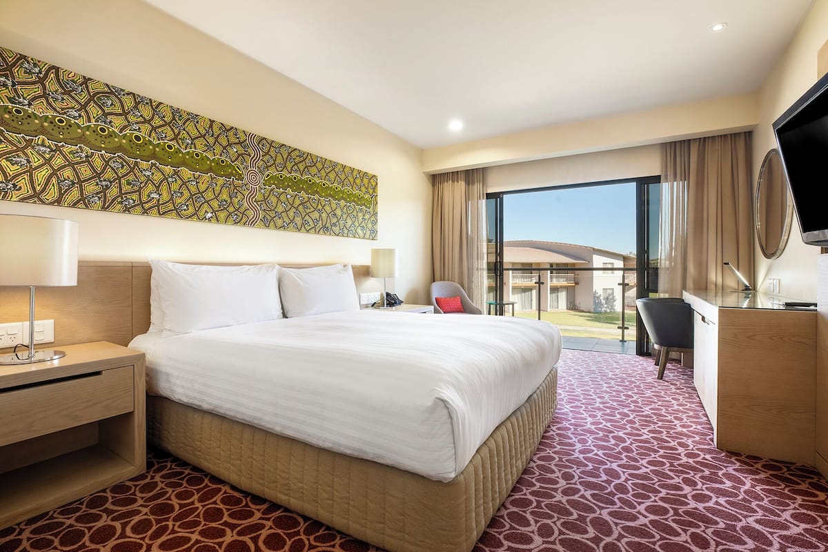 A hotel room with a large bed, a desk, a chair, and a television.